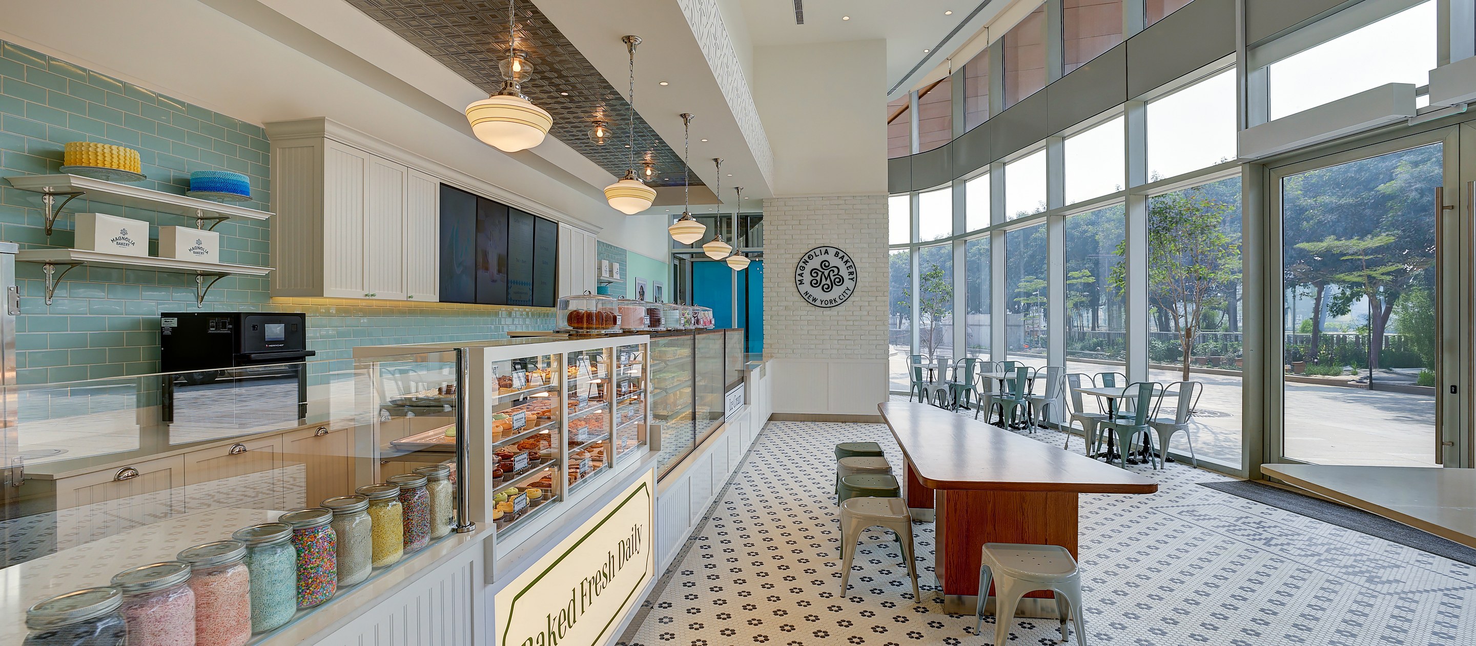 Looking down the counter towards the window seating in a Magnolia Bakery store operated by Spago Foods